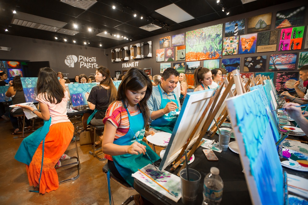 large team of people painting in studio