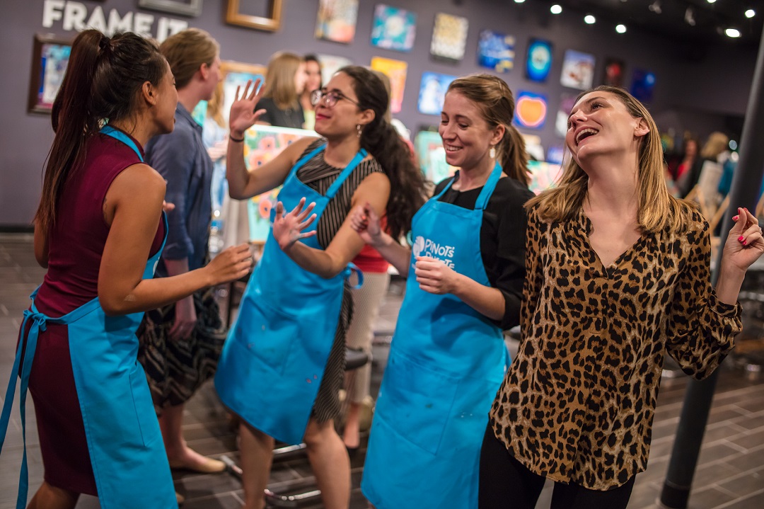 four girls in nice outfits and painting aprons, dancing